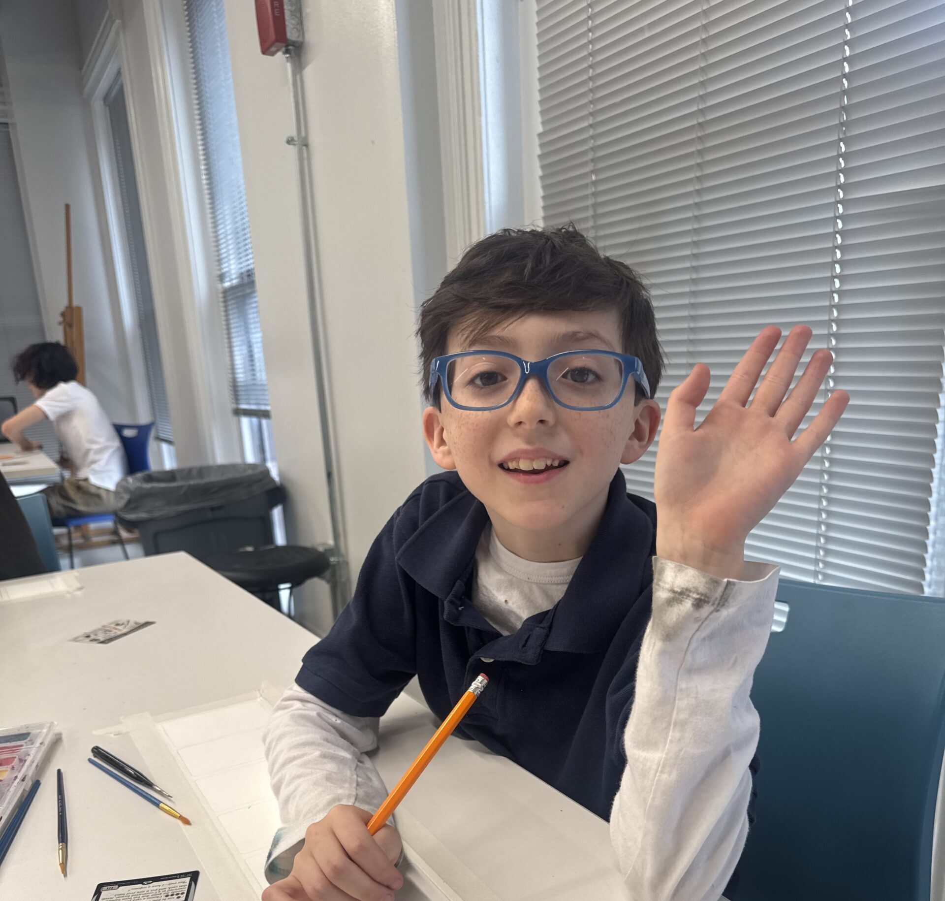 Student raising his hand in the air in the classroom