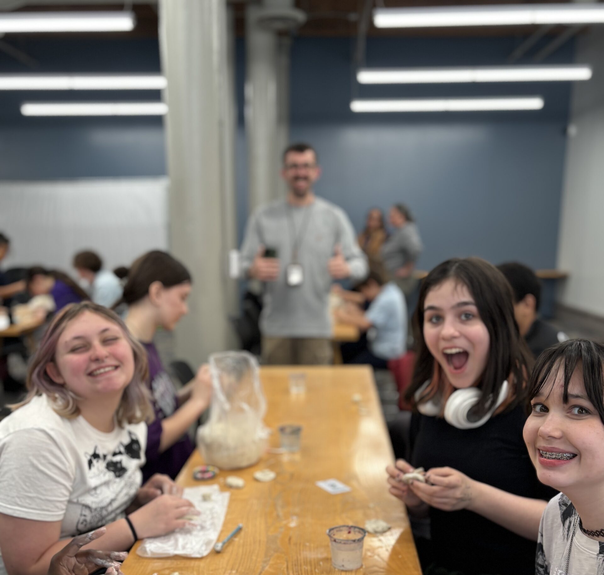 Students smiling at the camera excited to show their art