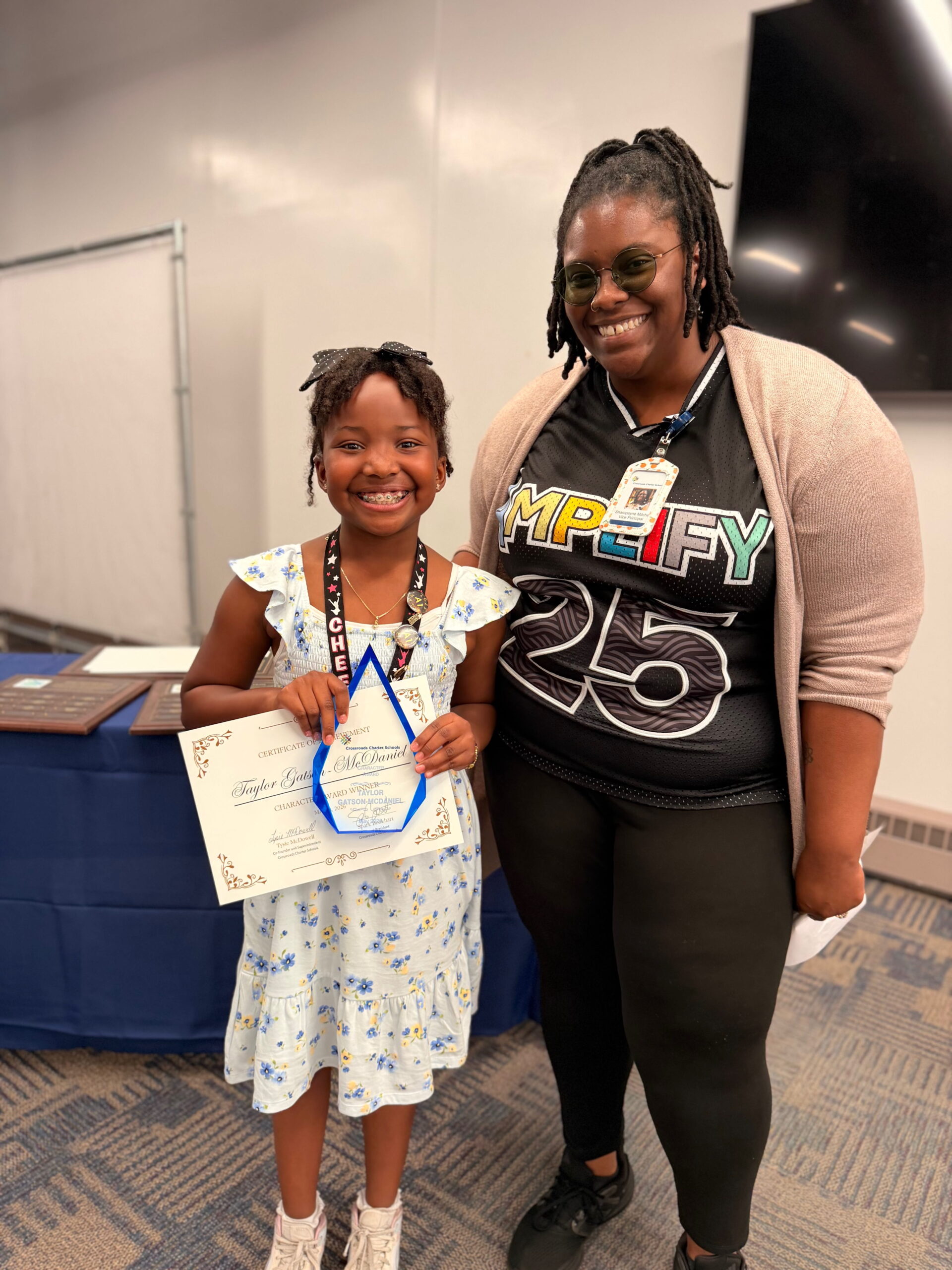 Teacher standing with student holding award in hand