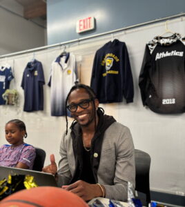 Adult sitting at a table smiling with a young student